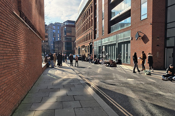 People make do with sitting on the pavement due to the paucity of good open space. Ancoats, Manchester.